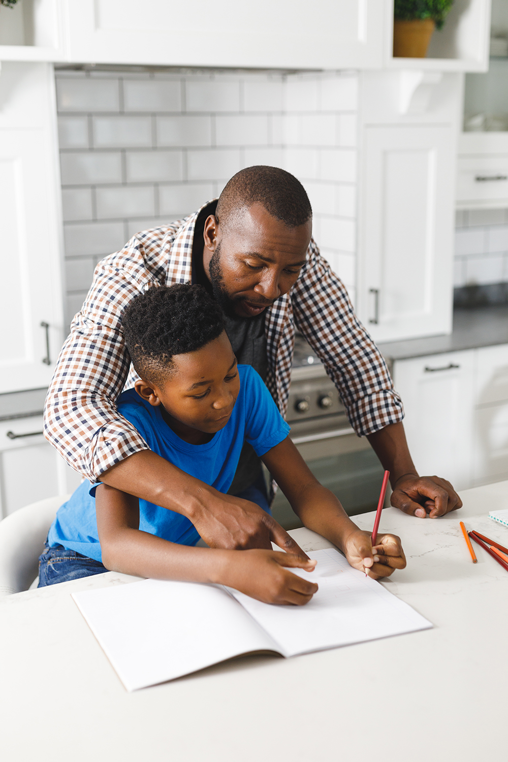 African American Father And His Son In Kitchen, Doing Homework Together. Family Spending Time At Home.
